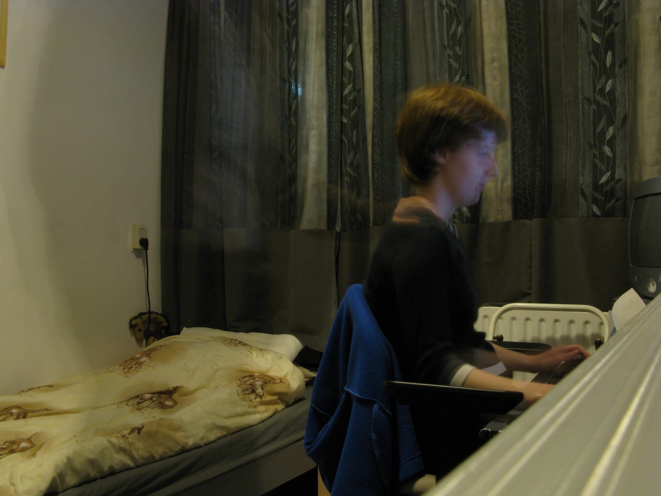 a boy using his laptop while in a bedroom