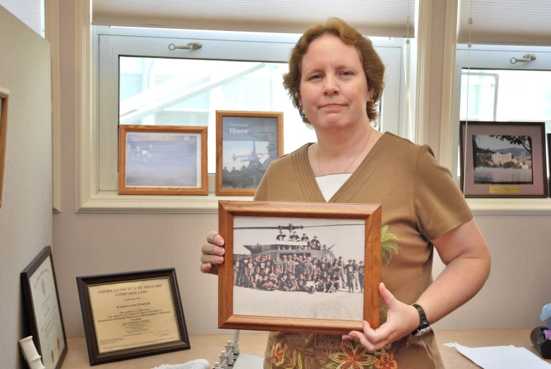 a woman holds up her framed pograph while showing off her award