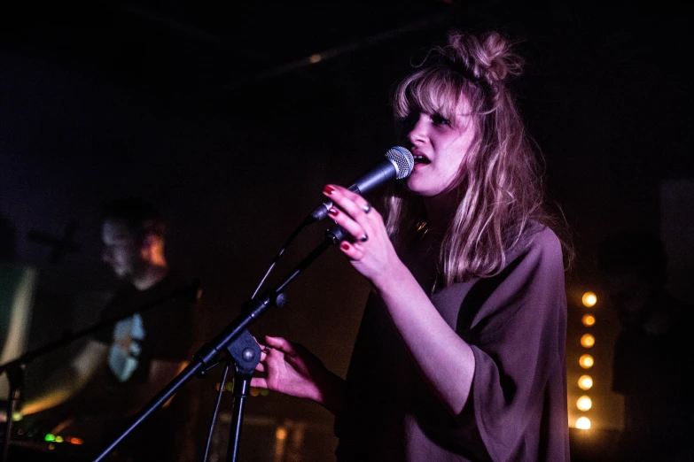 a woman singing into a microphone in front of people