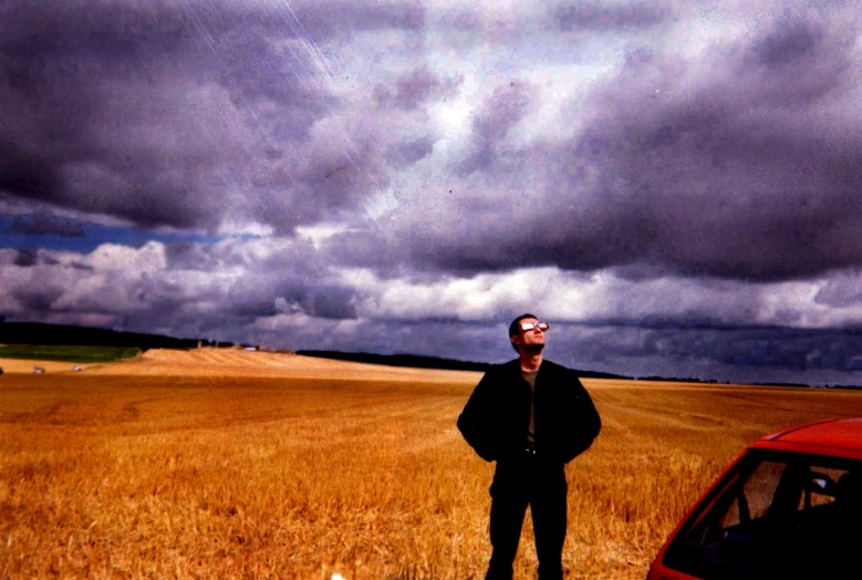 man standing by car in large field of grain