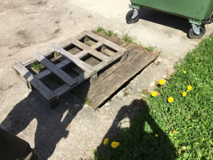 a green trash can next to some pallets