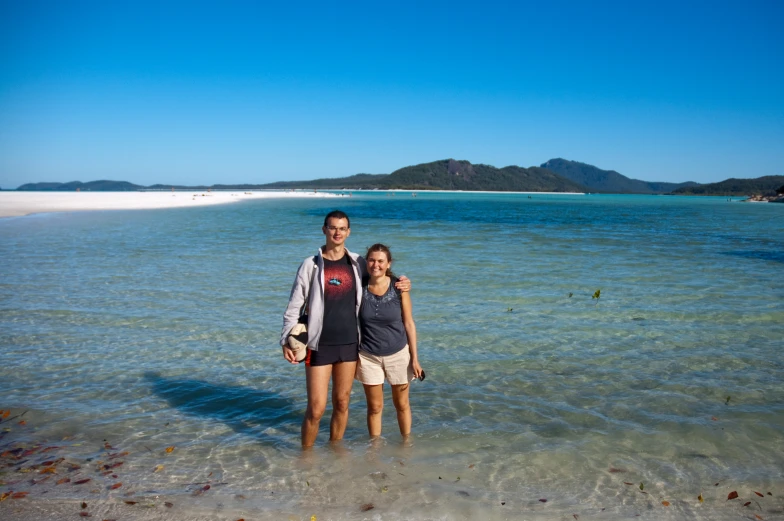 two people posing in shallow water near the beach