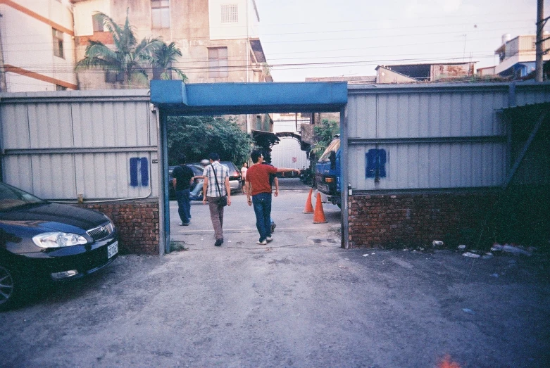 two people walking down a sidewalk under a blue archway