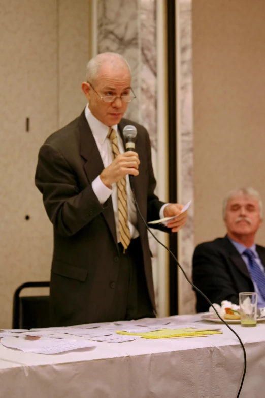 a man wearing a suit stands in front of a microphone