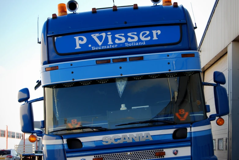 a blue double decker bus parked next to a building