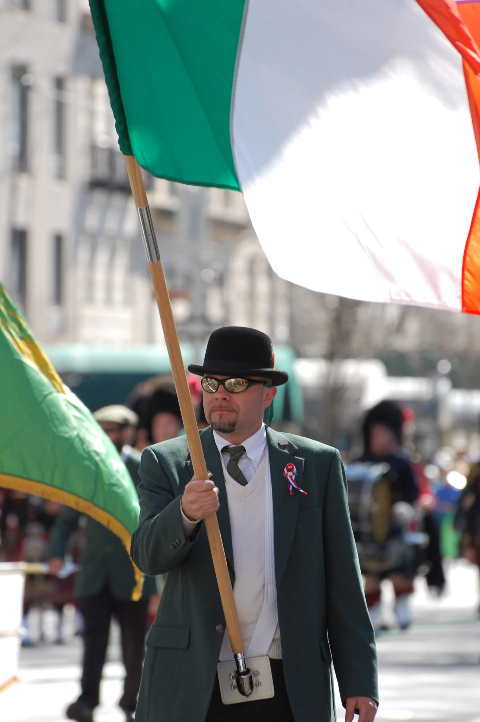 a man dressed in business attire carrying a flag and a stick