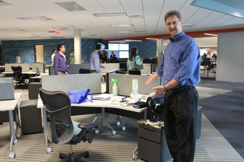 a man standing in an office cubicle with his hands on a desk