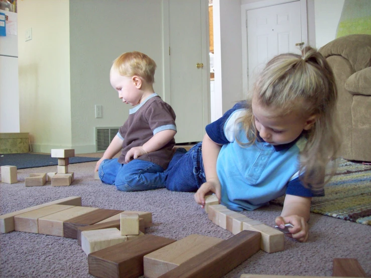 two young children playing with blocks in the floor