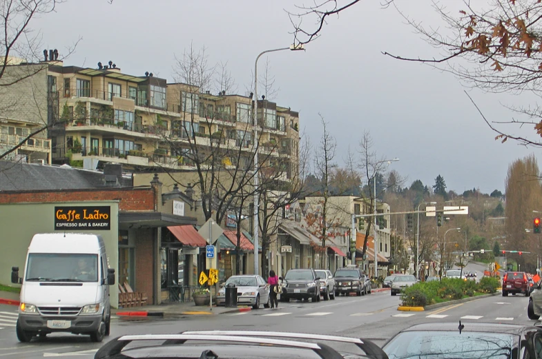 a small city street with cars, pedestrians and buildings