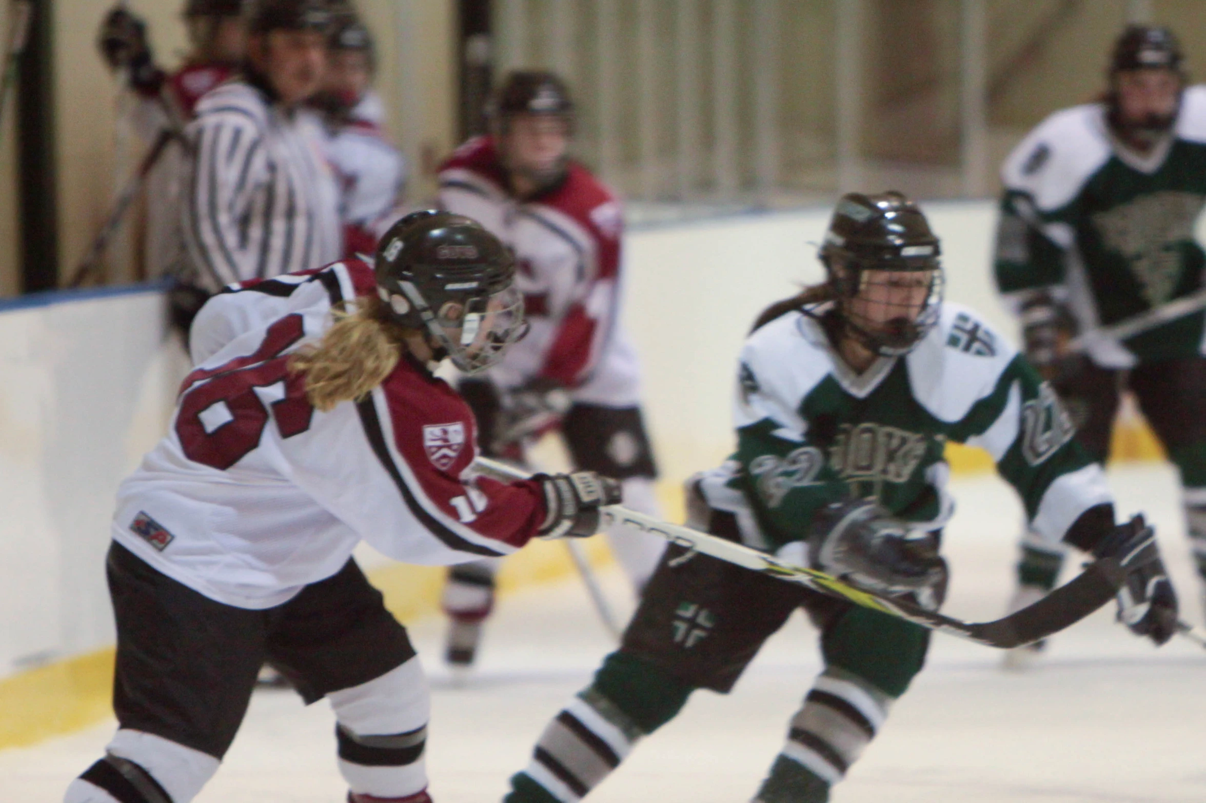 a young woman wearing a green uniform skates with a hockey stick