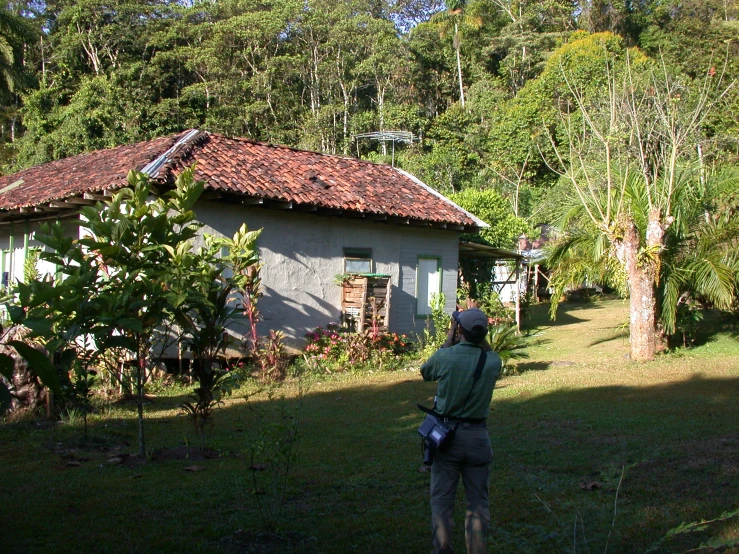 a person walking toward a small hut with trees in the background