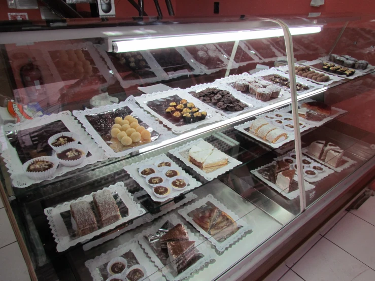 a glass display case with various varieties of chocolates and pastries