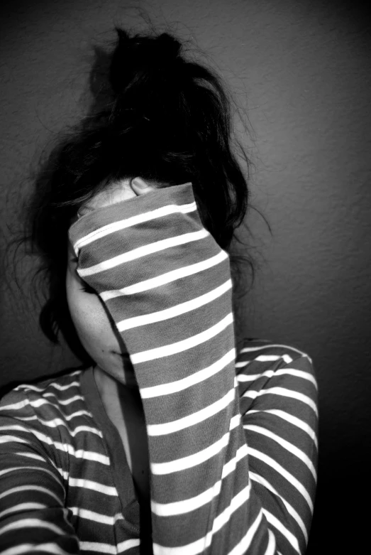 woman in striped shirt hiding under her sweater