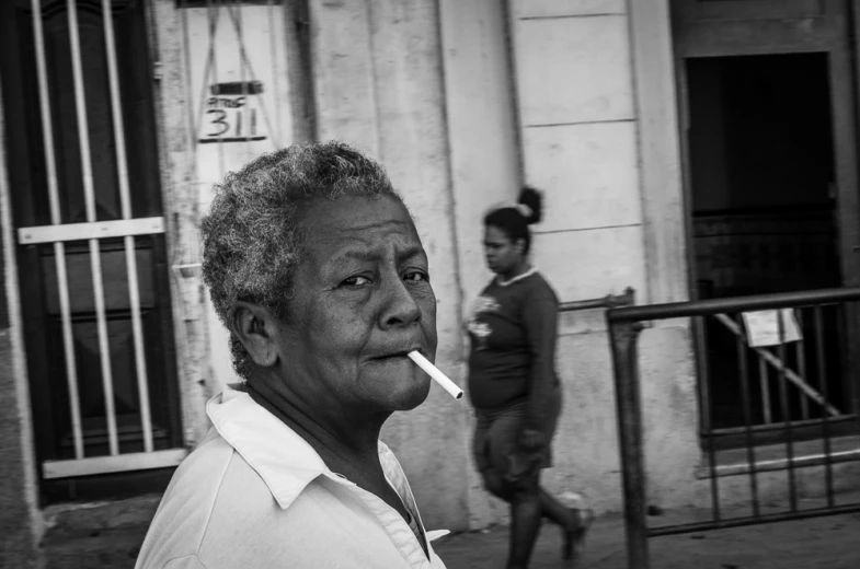 an old woman walking down a street with a cigarette in her mouth