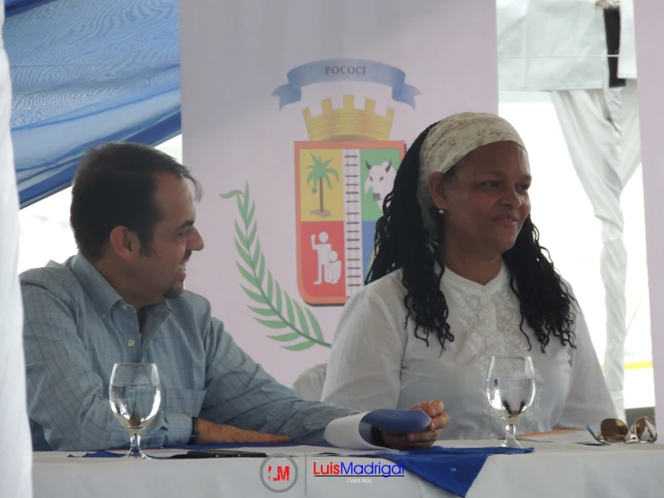 a woman in white sitting next to a man at a table