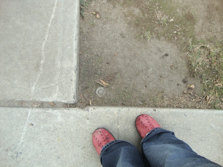 a person standing outside on a sidewalk with red shoes