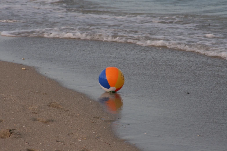 a beach ball on the shore of an ocean