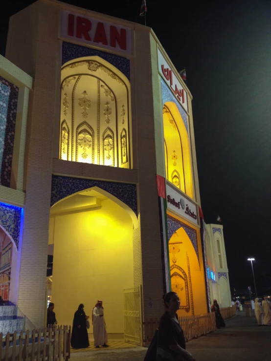 people are walking past an intricately lit building