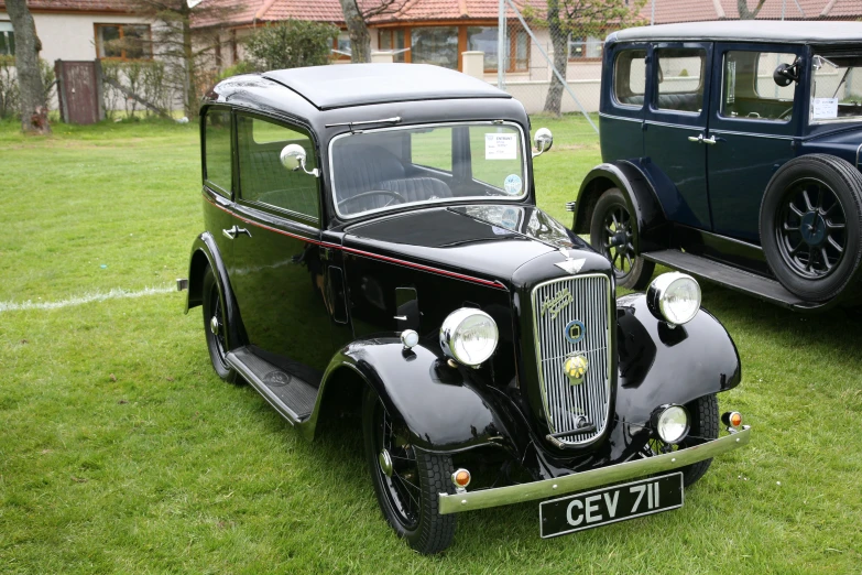 two black vintage cars on display on green grass