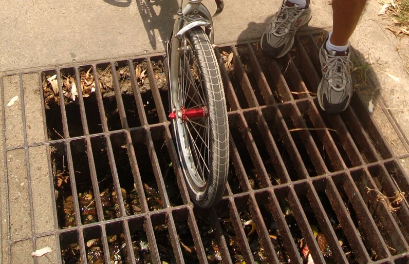 the person is wearing sneakers and standing next to a bicycle