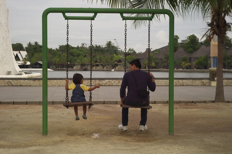 father and daughter at a park on a swing