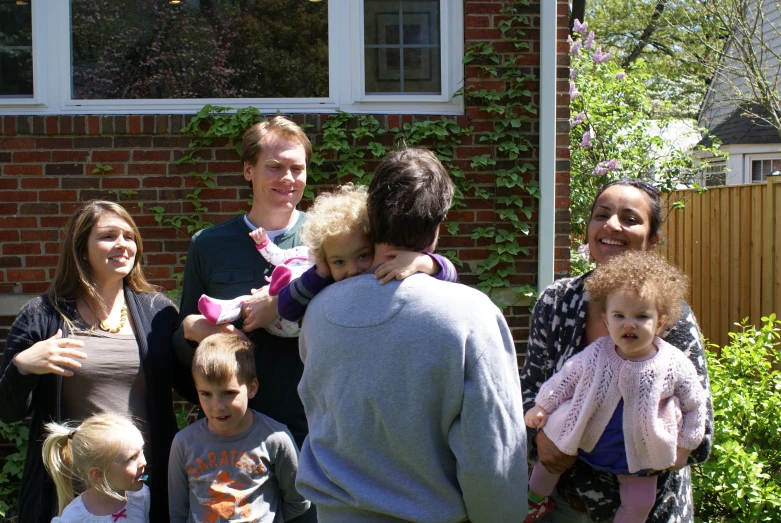 a woman holding a baby between two adults and a child