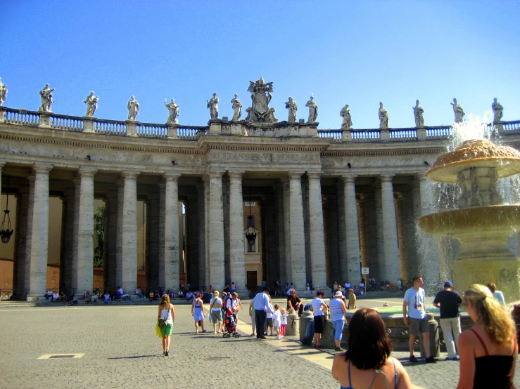 the crowd is outside of the large building with the columns