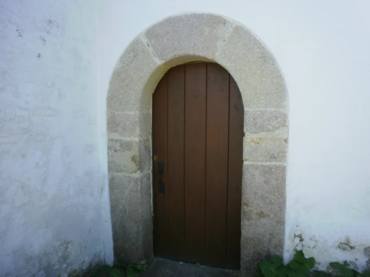 a door with a circle arch next to a small building