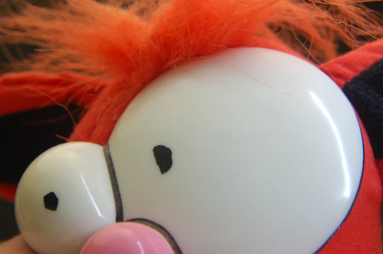 a little white toy with red hair on it's head