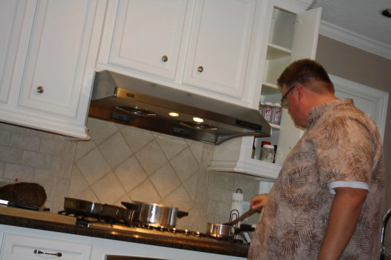 a man in the kitchen is cooking on his stove