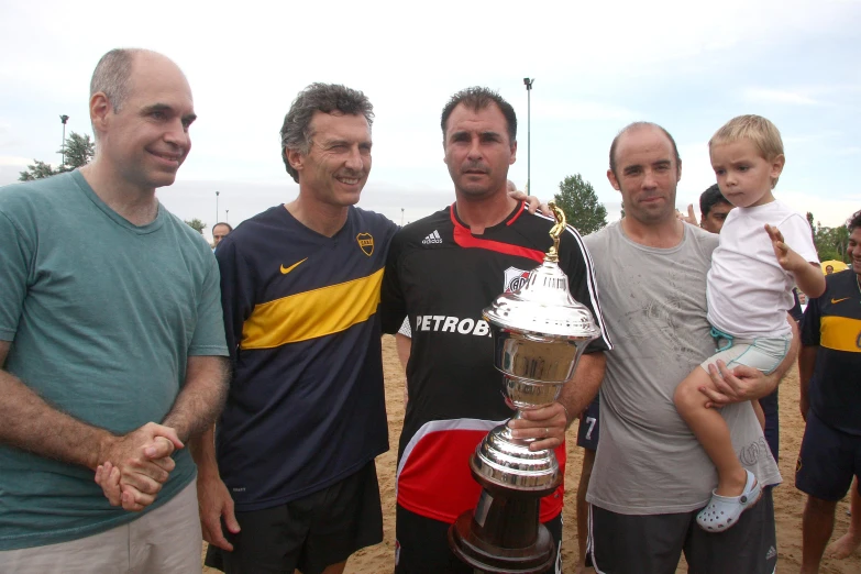 a group of men standing next to each other holding up a trophy