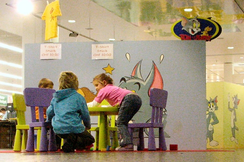 several children are sitting at the table and looking at soing