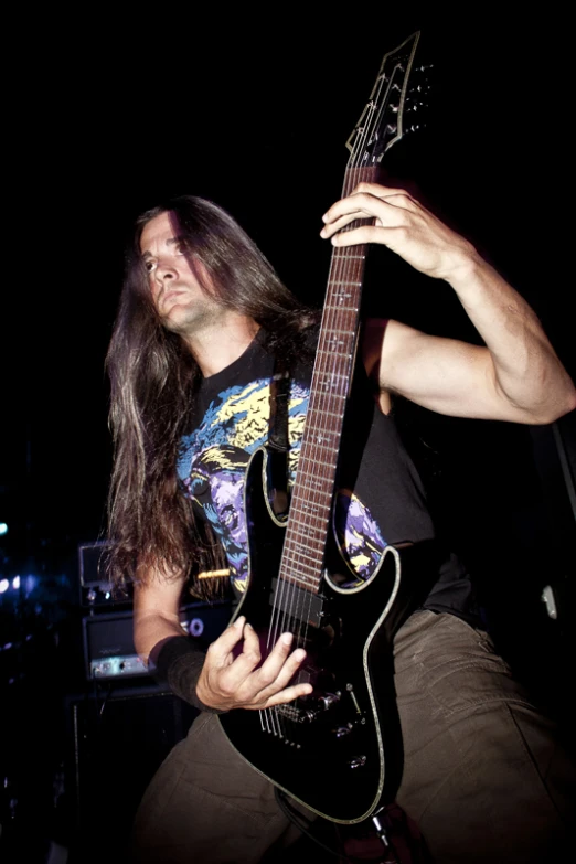 a man playing a black electric guitar with the light shining in his eyes