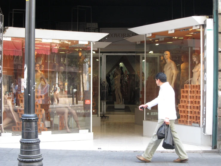 a man is walking down a sidewalk past shops