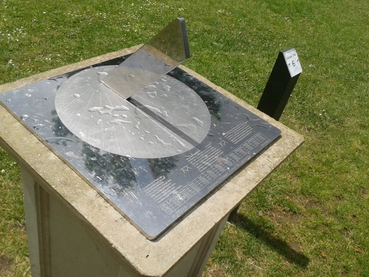 a sculpture in the grass with a piece of metal on it