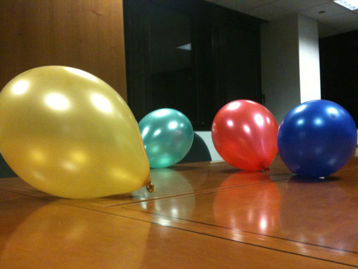 several colorful balloons sitting on top of a hard wood floor