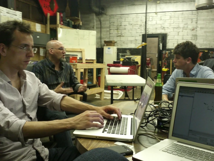 two guys and an older man are working on a laptop