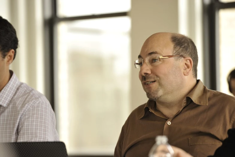 two men sitting on the table looking at a computer screen