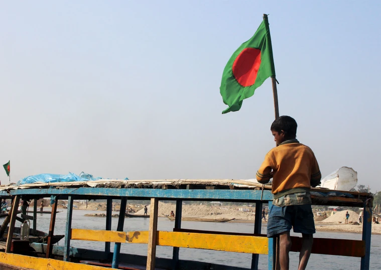 a man is standing on the front of a boat holding a flag