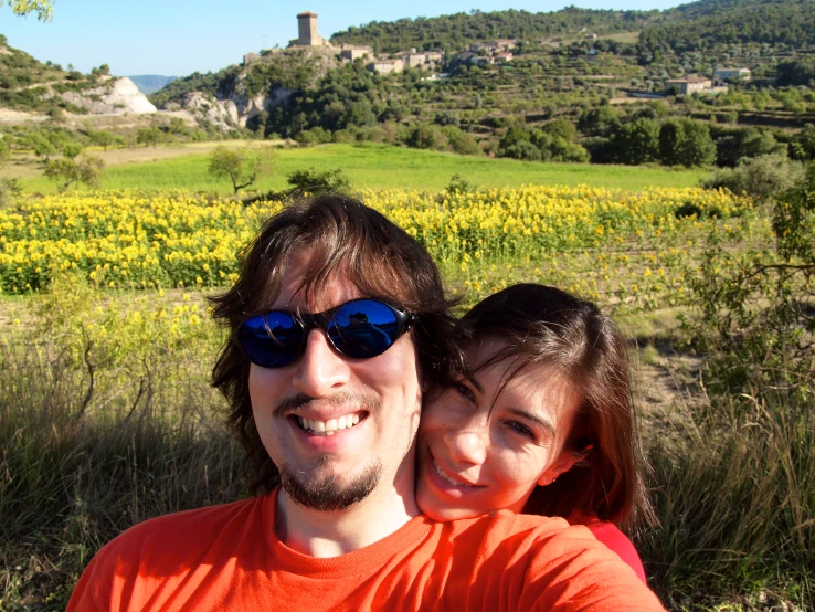 the man and the little girl are posing in front of some yellow flowers