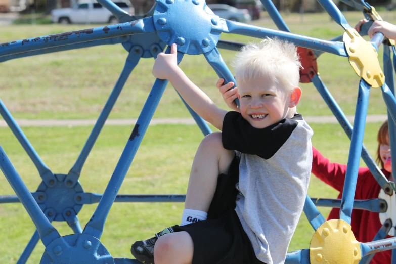 a  in grey shirt climbing on a blue structure