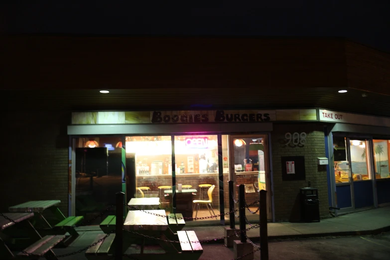 a lit up night time diner with chairs outside