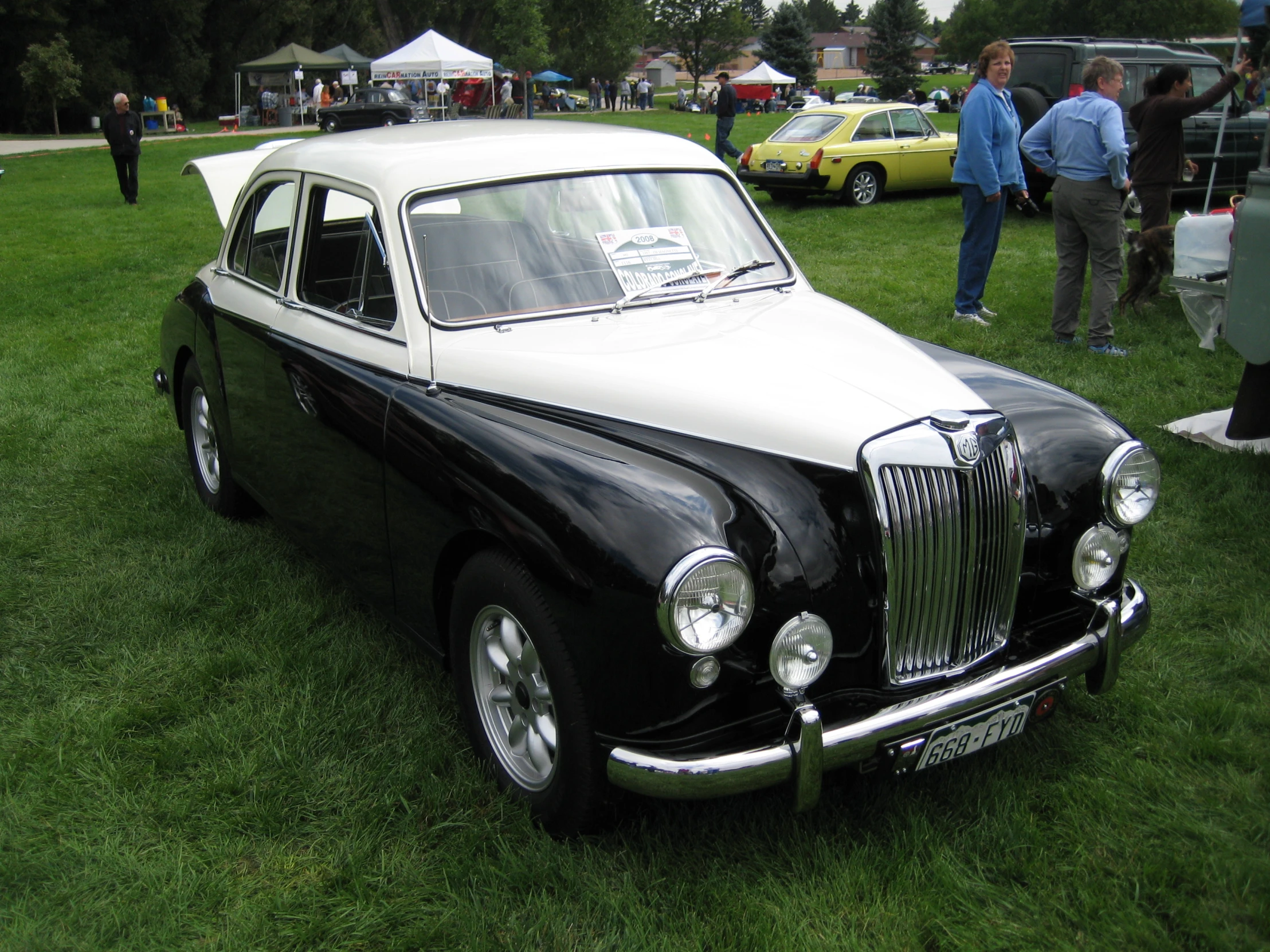 a black and white rolls royce parked in a field