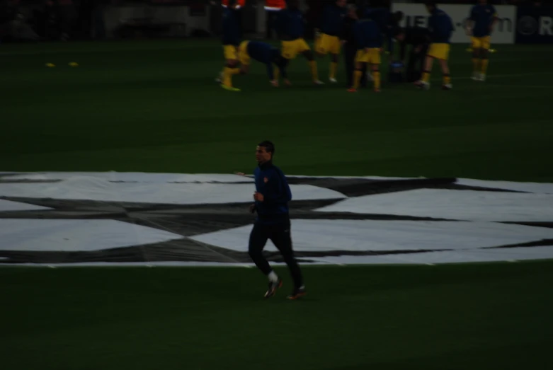 a man walking across a field holding a soccer ball