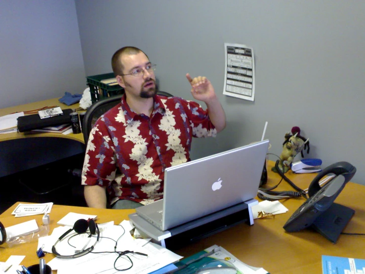 a man sitting in front of a laptop computer holding a piece of paper