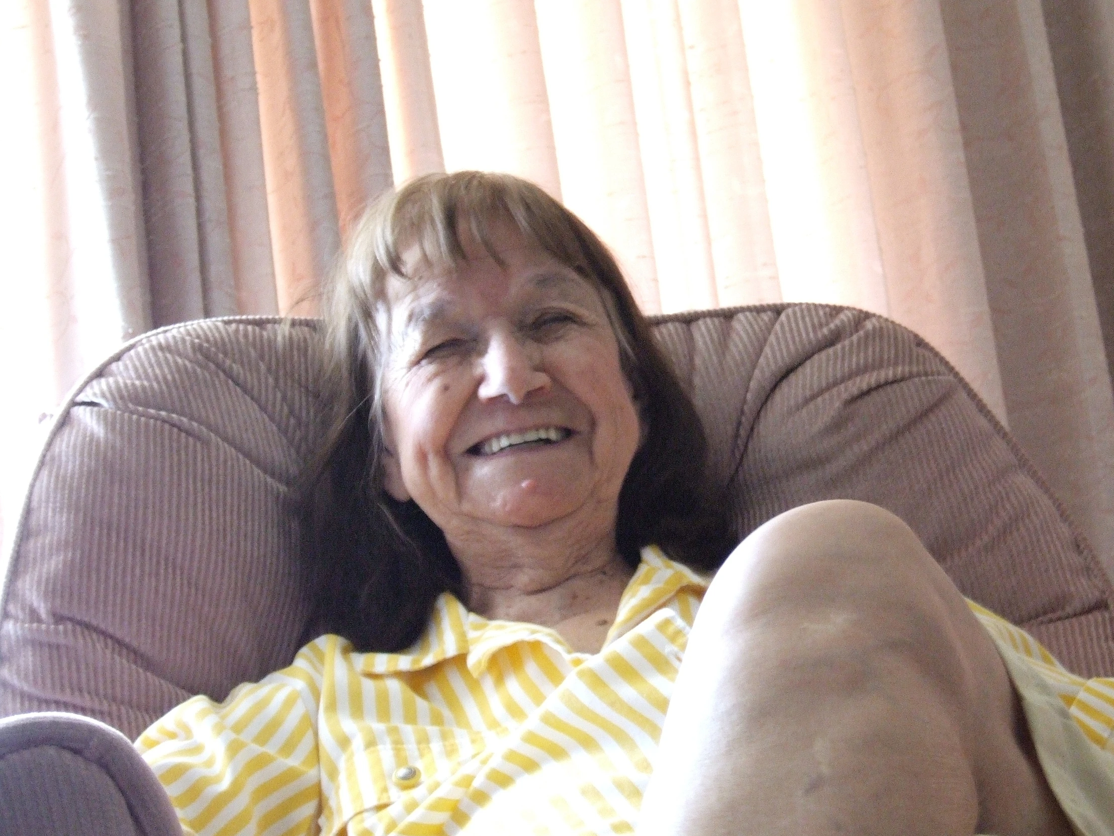 the elderly woman smiles while sitting in her home