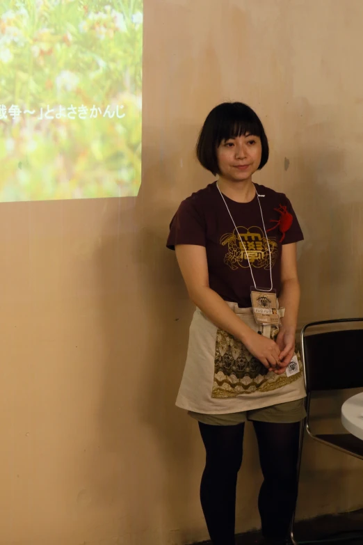 an asian woman in short skirt standing next to a projector screen