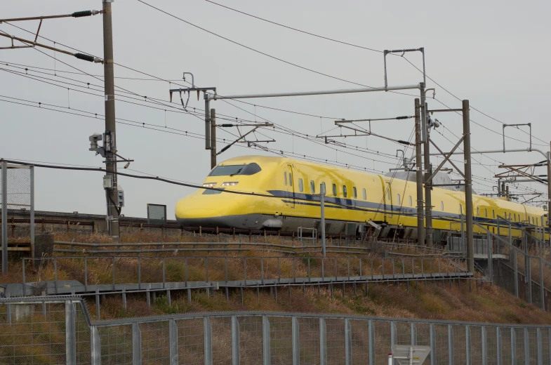 a very long yellow train is in the middle of a track
