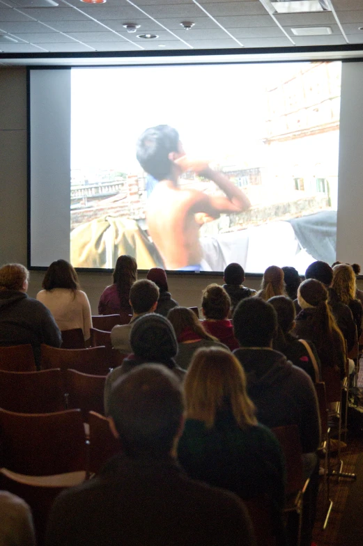 audience watching a performance on screen in a auditorium