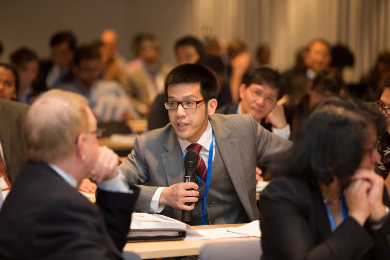 an audience listening to a man at the front of a room